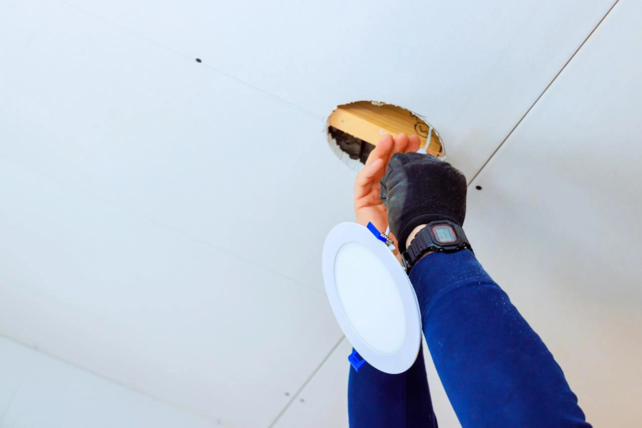 Licensed electrician repairing and replacing a ceiling LED downlight in a Brisbane home