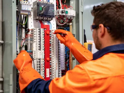 Electrician installing and servicing safety switches in a Brisbane electrical switchboard.